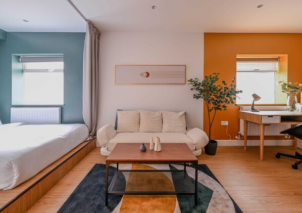 A modern bedroom with a bed, a sofa, a coffee table, and a desk.