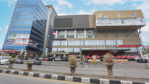 Un bâtiment moderne à plusieurs étages, doté de grandes fenêtres et d’une enseigne bien visible indiquant l’entrée d’un centre commercial.
