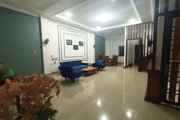 A spacious living area with a blue sofa set, a wooden coffee table, and a decorative wall with framed pictures. - Hotel O Suka Maju Homestay Syariah (Medan)