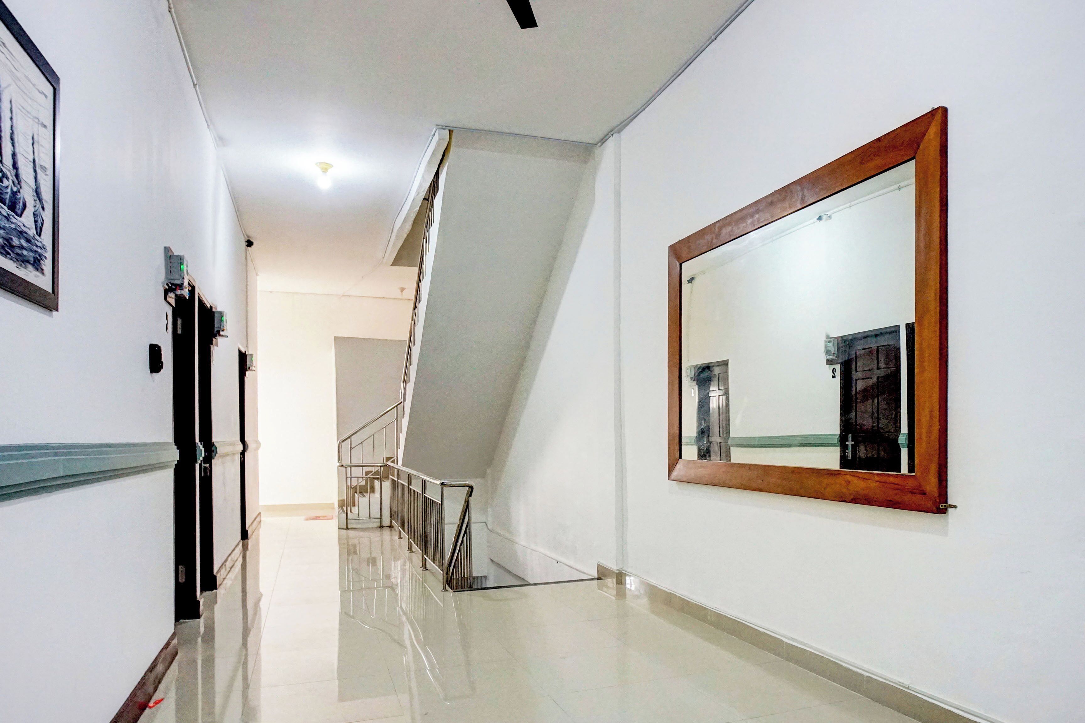 A hallway with a polished floor, a staircase, and a large mirror on the wall.