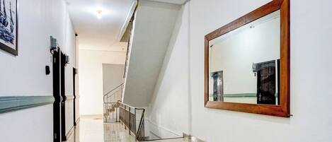 A hallway with a polished floor, a staircase, and a large mirror on the wall.
