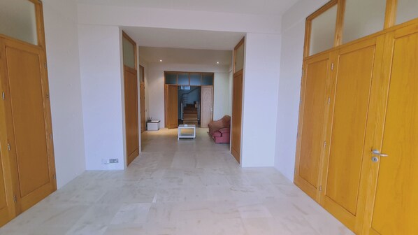 Un passadís amb portes de fusta, una escala i un sofà rosa.