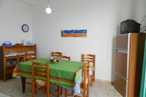 Cozy dining area with a table and chairs, TV, and clock.