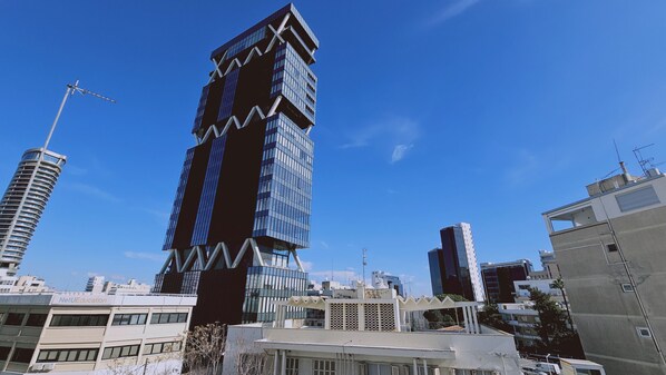 A modern high-rise building with a unique zigzag design, surrounded by other buildings in an urban setting.