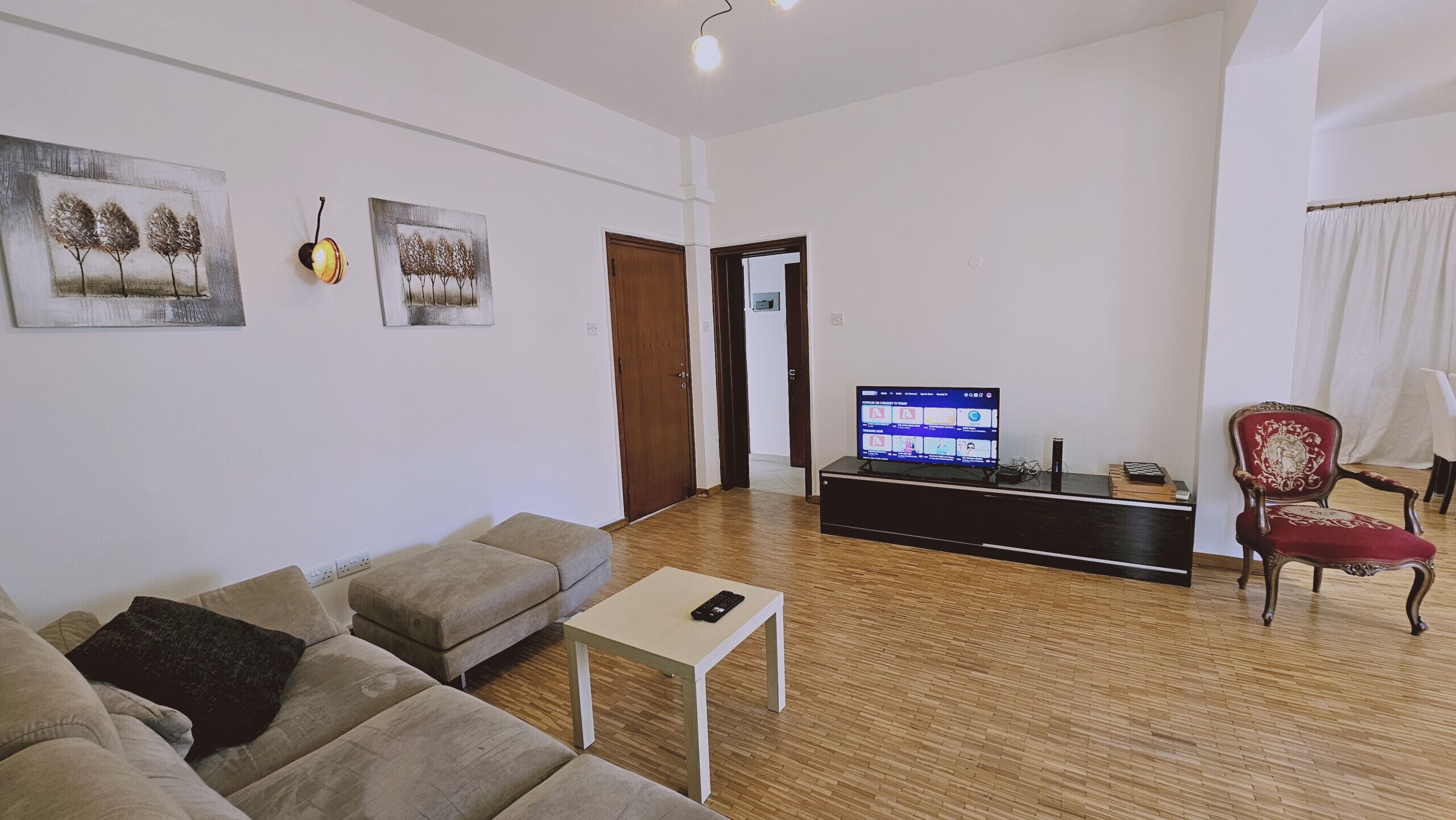 A living room with a sofa, a coffee table, a TV, and a red chair.