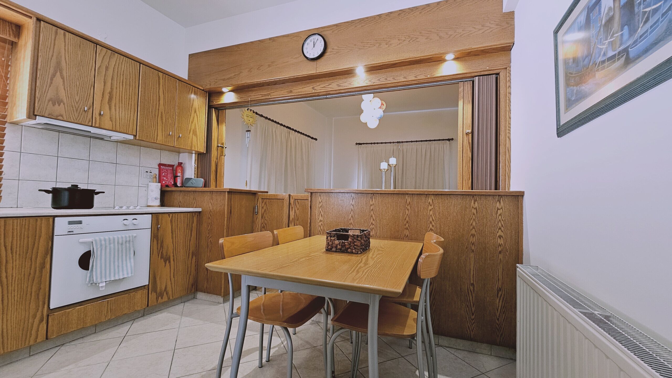 A kitchen with wooden cabinets, a stove, a sink, and a dining table with chairs.