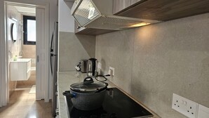Una cuina moderna amb fogó integrat, una paperera i una olla damunt el taulell.