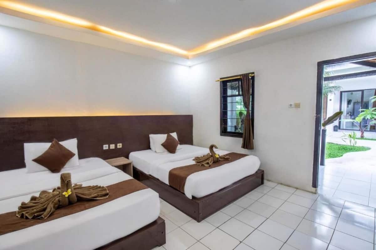 Una habitación de hotel con dos camas, una ventana con cortinas y vistas al exterior.