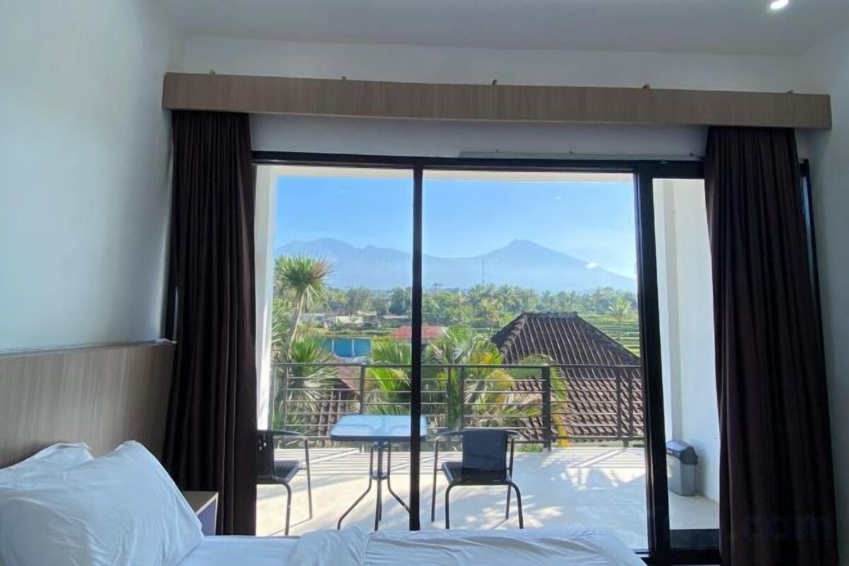 A hotel room with a large sliding glass door leading to a balcony with a table and chairs.