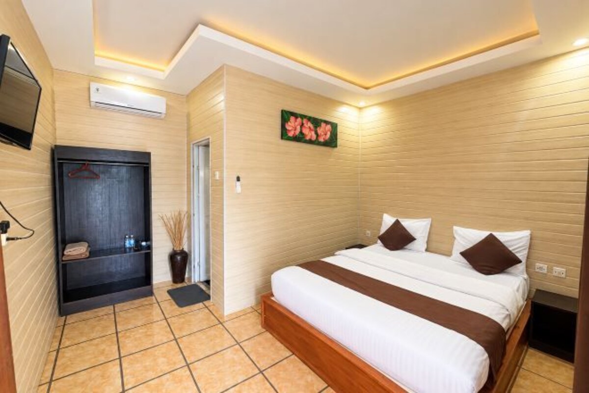Een hotelkamer met een bed, een televisie, een kledingkast en een zithoekje.