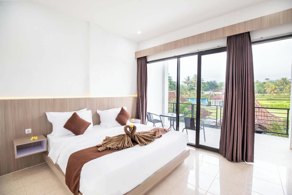 Una habitación de hotel moderna con una cama grande, una mesita de noche y un balcón con vistas al campo.