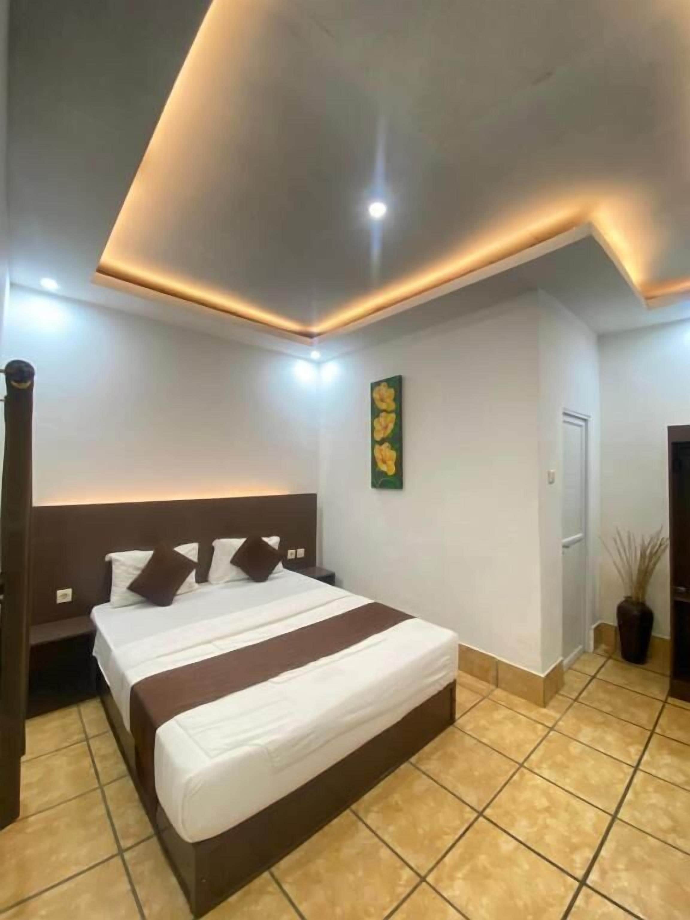 A hotel room with a large bed, a nightstand, a wall-mounted artwork, and a door.