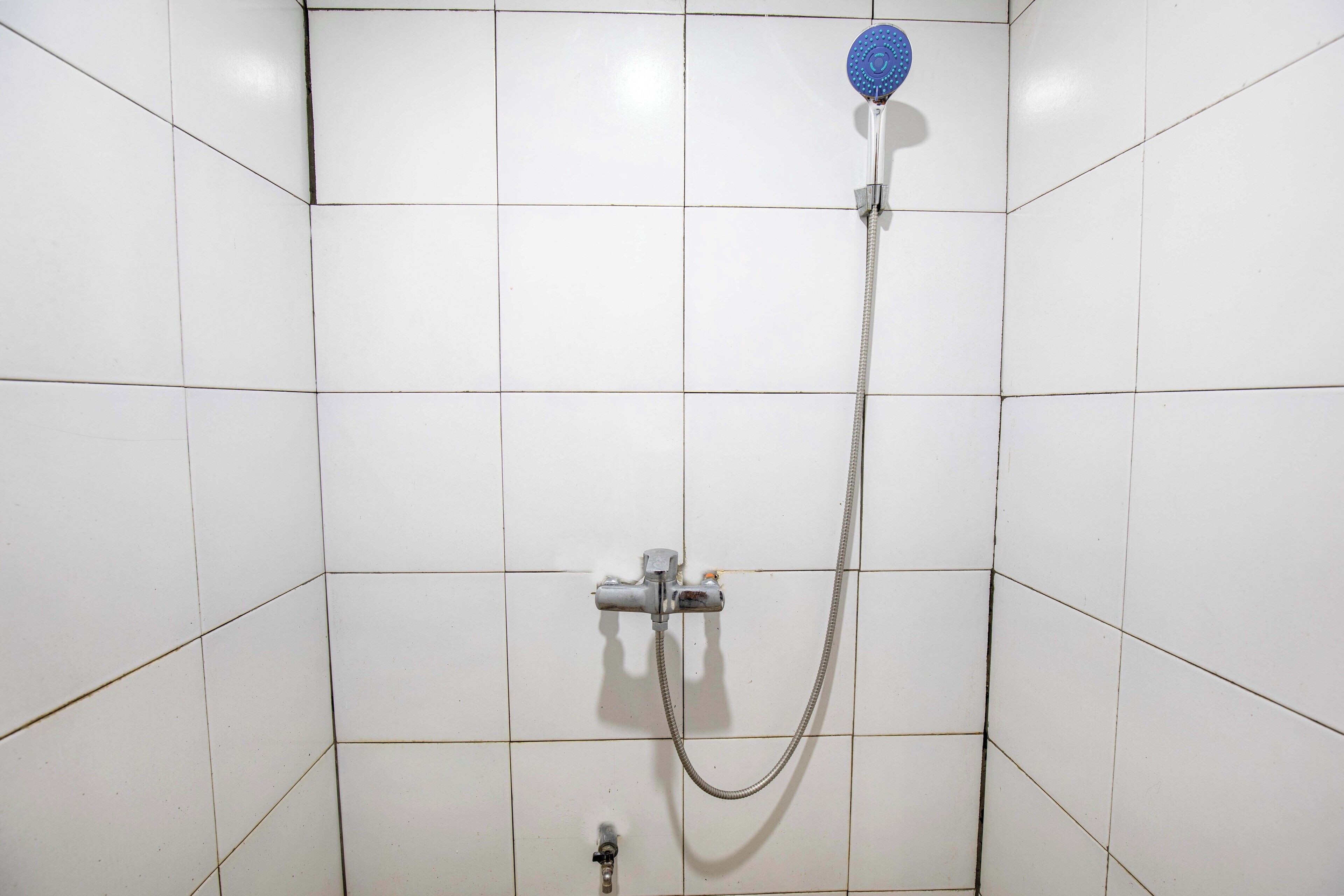 Eine Dusche mit Handbrause und einarmiger Armatur.