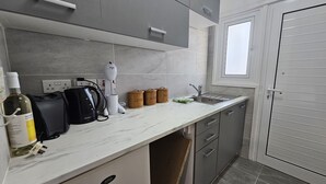 Une cuisine moderne dotée d’un plan de travail en marbre, d’une bouilloire, d’une bouteille de vin et de trois récipients en bois étiquetés « café », « sucre » et « thé ».