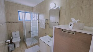 Une salle de bain avec une douche à parois de verre, des toilettes, un lavabo et un meuble-lavabo avec un miroir.