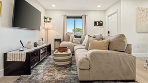 A modern living room with a flat-screen TV, a sofa, a coffee table, and a console table with decorative items. - Good Vibes Sanctuary, Central Location South Miami (Cutler Bay)
