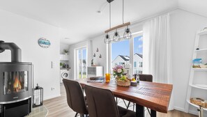Cozy living space with a central dining table, stove, and large windows offering a neighborhood view.