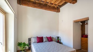 Een slaapkamer met een houten bed, een groot raam, een potplant en een houten kledingkast.