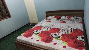 A bedroom with a bed, a window with decorative bars, and a door. - Hotel O Dian Asih Rooms (Demak)
