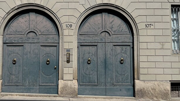 A building facade with two large, dark wooden doors, each marked with a number (109 and 107).