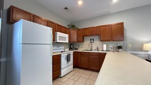 A kitchen with wooden cabinets, a white refrigerator, a microwave, a stove, and a sink. - Elegant 2BR | Modern Amenities & Convenient Flair (Johnson City)
