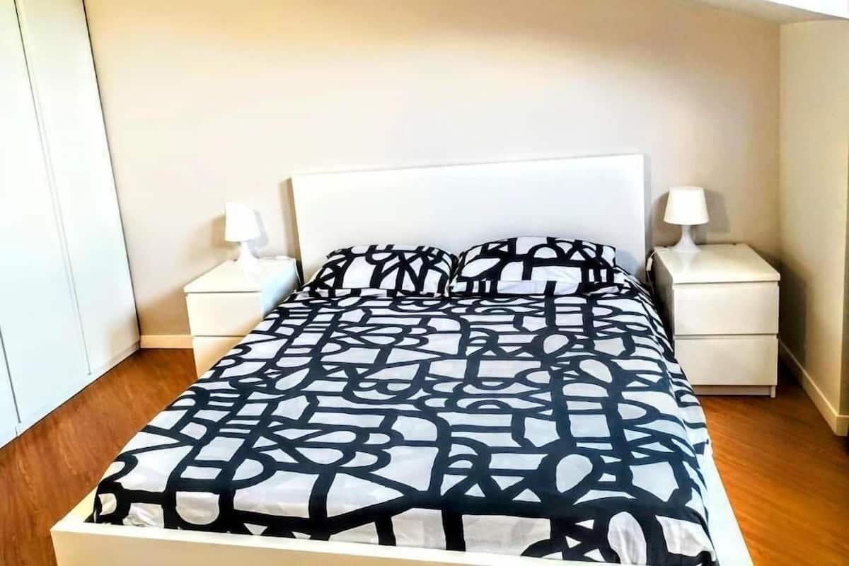 A bedroom with a bed, two bedside tables, and a nightstand.