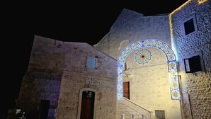 Un bâtiment historique doté d’une façade en pierre, d’une porte en bois et d’une arche décorative illuminée de lumières colorées.
