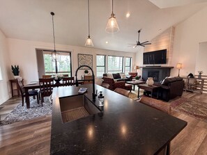 A spacious living area with a large island, seating arrangements, and a fireplace. - Perfect Spot | Private & Wooded Area | Sleeps 10 (Columbia Falls)