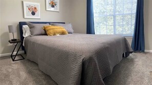 Une chambre à coucher avec un grand lit, une table de chevet, une lampe et deux tableaux encadrés au mur.