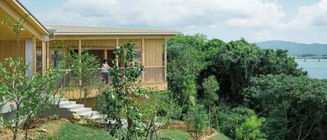 A wooden cabin with a balcony overlooking a lush landscape and a body of water.