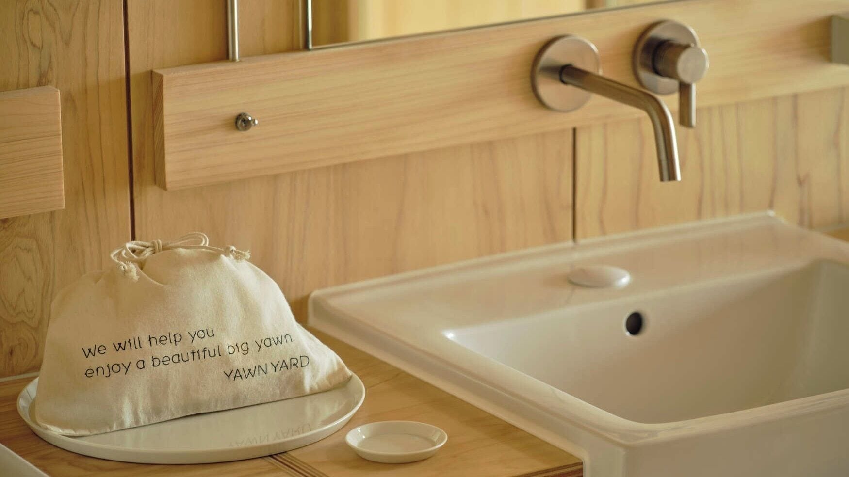 Une salle de bain avec un meuble-lavabo en bois, un évier et une serviette portant un message.