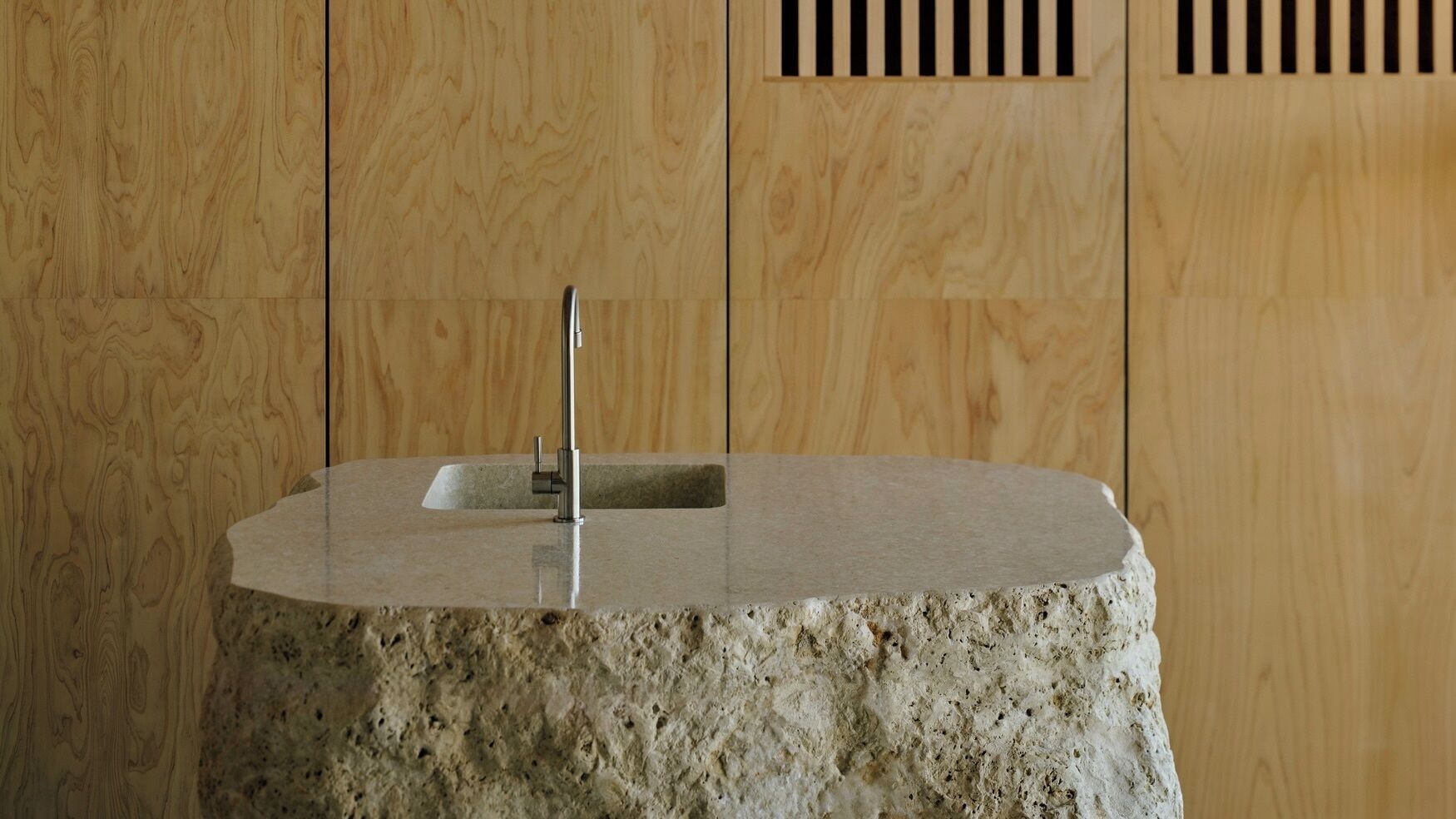 A stone sink with a modern faucet in a room with wooden paneling.