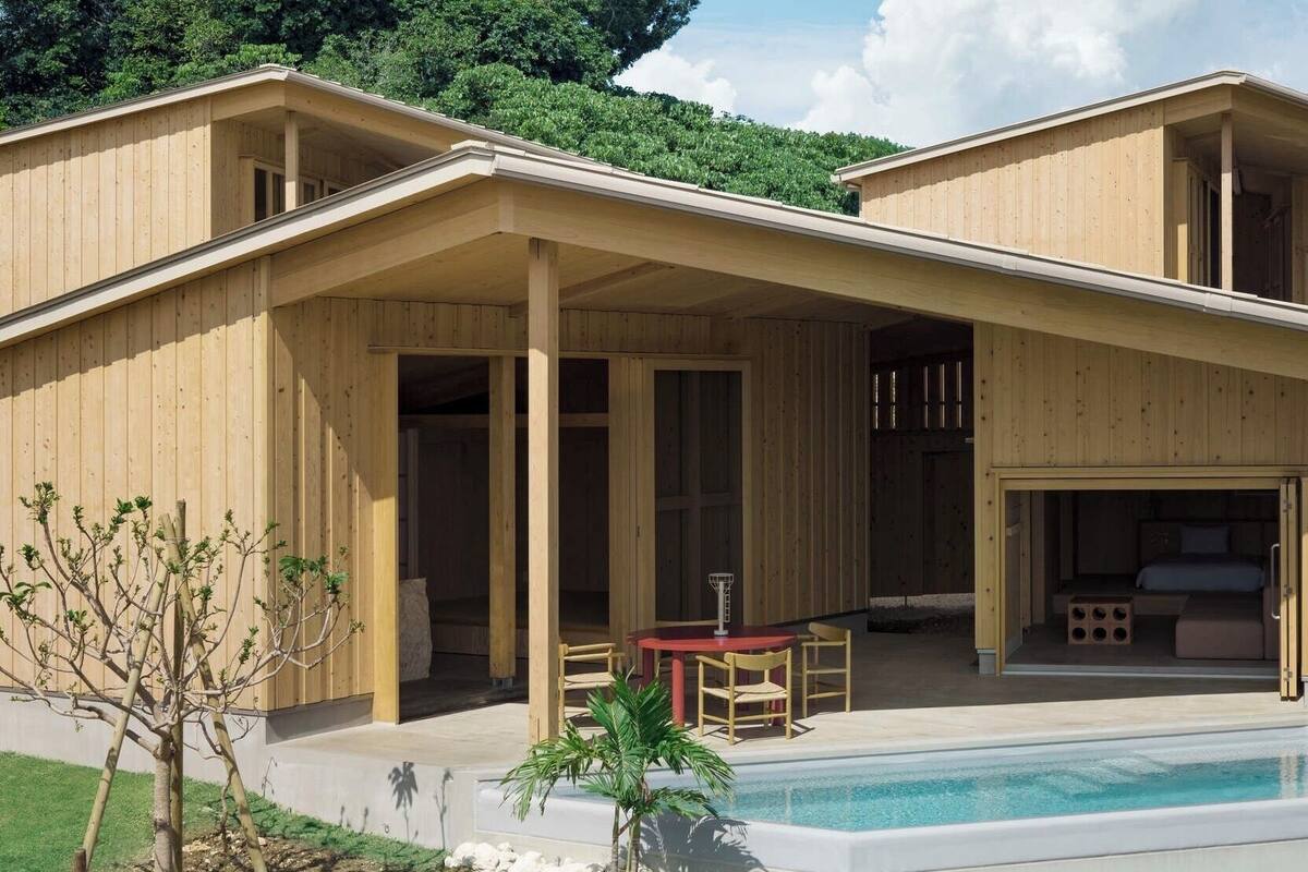 Een modern houten huis met een overdekte patio, een zwembad en een slaapkamer met een schuifdeur.