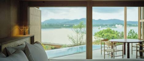 Ein Schlafzimmer mit großem Fenster mit Blick auf ein Schwimmbecken und Berge.