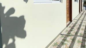 A corridor with a tiled floor, large windows with curtains, and wooden doors. - Mactan Hostel (Lapu-Lapu)