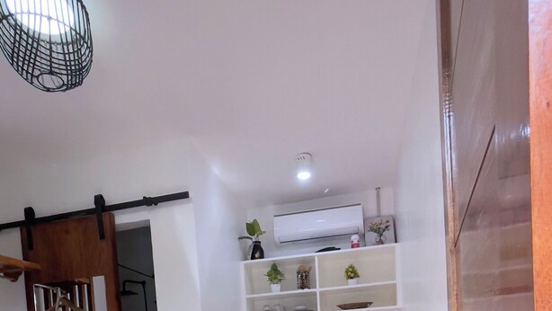 A compact hotel room with a bed, a small kitchenette, a wooden bench, and a wardrobe. - Mactan Hostel (Lapu-Lapu)