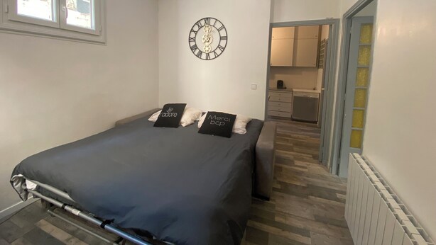 Un dormitorio con una cama, un reloj de pared y vistas a la cocina.