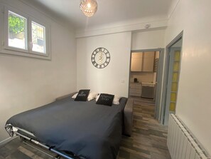 Un dormitorio con una cama, un reloj de pared y vistas a la cocina.