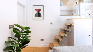 Un intérieur moderne avec un escalier, une œuvre d’art encadrée et une plante en pot.