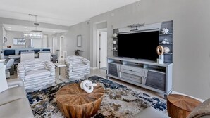 A modern living room with a large flat-screen TV, a wooden coffee table, and a patterned rug.