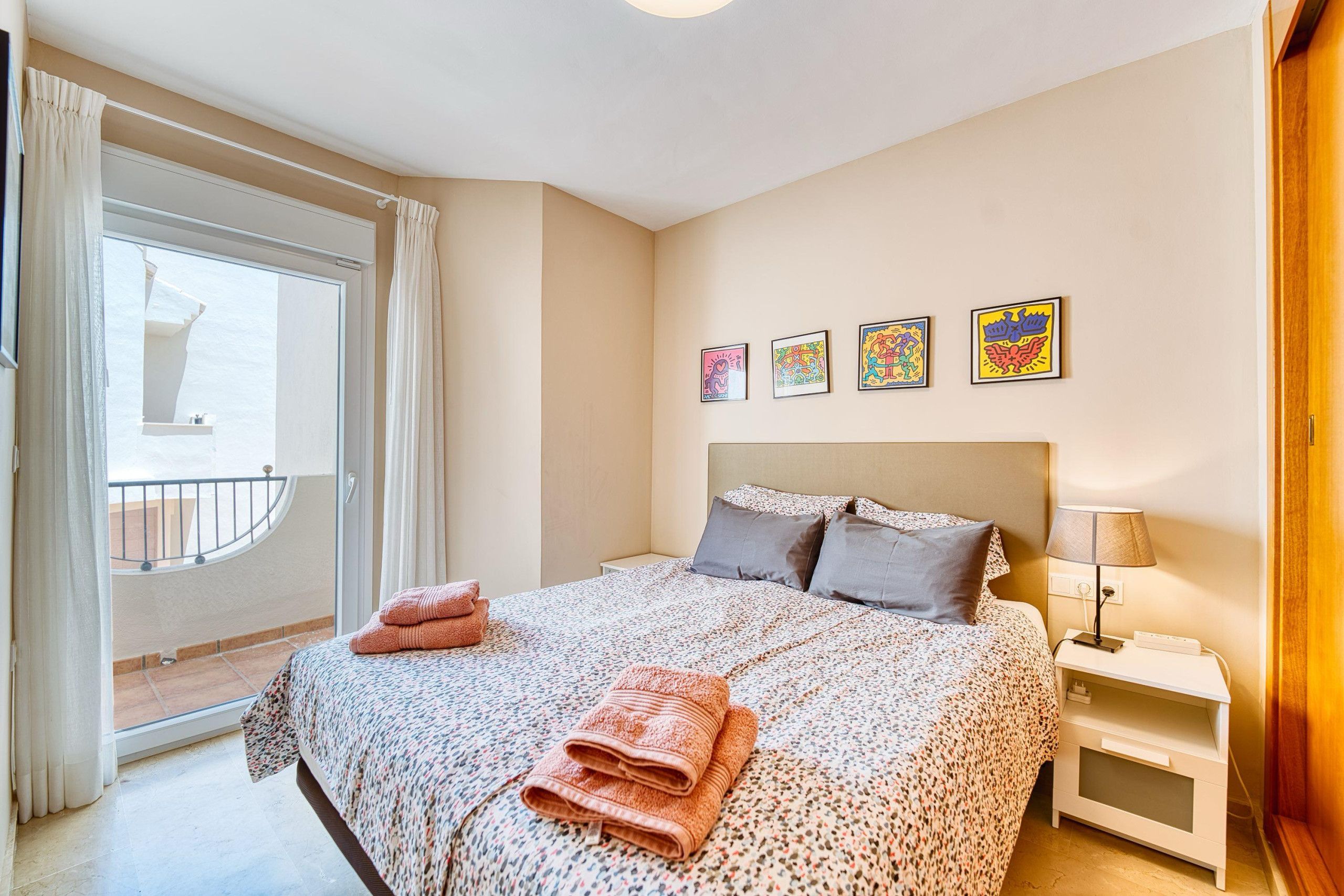 Een hotelkamer met een bed, nachtkastje, lamp en een raam met gordijnen.