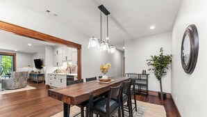Un comedor moderno con una mesa de madera, sillas negras e iluminación colgante.