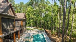 Una casa con piscina rodeada de bosque.