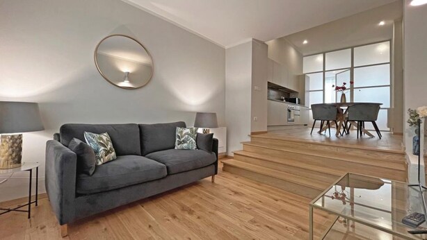 Un salon moderne avec un canapé gris, une table basse en verre et un coin repas comprenant une table et des chaises.