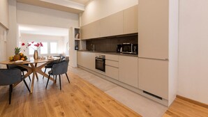 Une cuisine moderne dotée d’un îlot central, d’appareils électroménagers intégrés et d’un coin repas avec des chaises et une table.