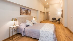 Une chambre à coucher avec un grand lit, des lampes de chevet, un tableau au mur et un bureau avec une chaise.