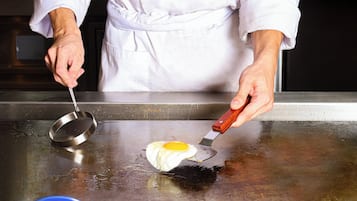 A person cooking an egg on a hot surface.