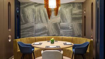 A modern dining area with a round table, two blue chairs, and a central decorative piece.