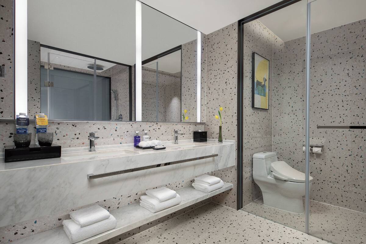 A modern bathroom with a glass shower enclosure, a marble vanity, and a large mirror.