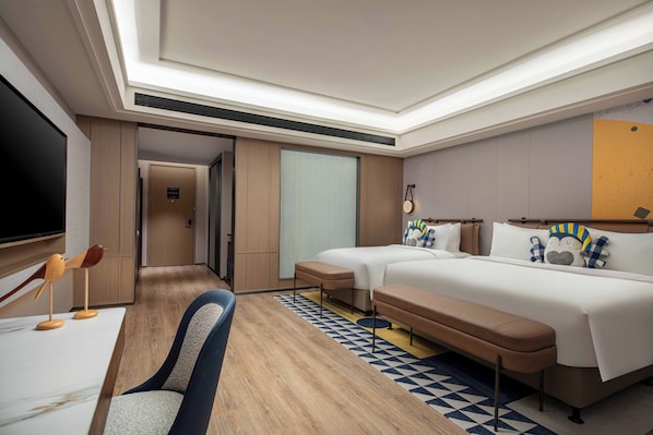 A modern hotel room with a large bed, a sofa, a TV, and a desk.